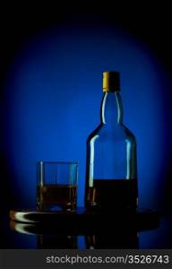 whiskey bottle and glass on wooden tray, blue background