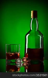 whiskey bottle, ice and glass, green background