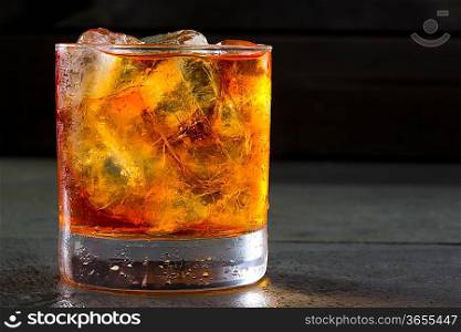 Whiskey whisky on the rocks on glass over gray black background