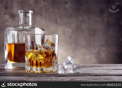 Whiskey with ice cubes on a wooden table. Whiskey with ice cubes