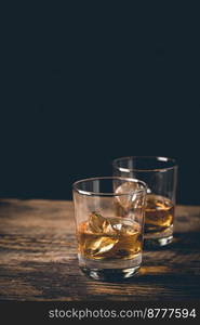 Whiskey with ice in glass on dark background, copy space. Whiskey with ice in glasses