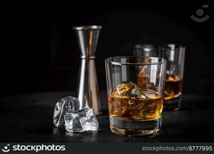 Whiskey with ice in glass on dark background, copy space. Whiskey with ice in glasses