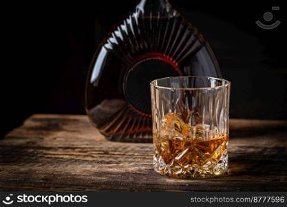 Whiskey with ice in glasses and bottle, dark background, copy space. Whiskey with ice in glasses