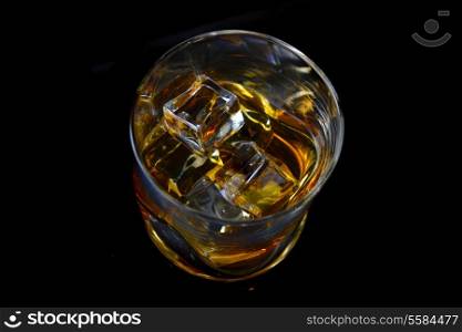 Whiskey with ice in simple glass on black background