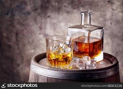 Whiskey with ice on wooden barrel with an iron rim. Whiskey with ice on wooden barrel