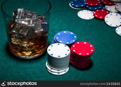 whisky with ice cubes casino chips stack green poker backdrop