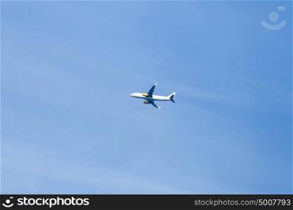 white airplane flying in a clear pale blue sky.