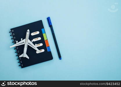 White airplane model with a checklist diary on blue background for travel planning concept