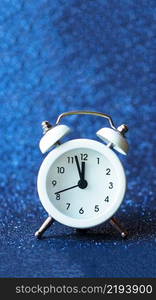 white alarm clock on a blue shiny background. copy space.