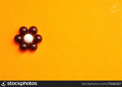 White and black balls packed in the shape of a flower isolated on an orange background