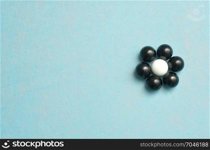 White and black balls packed in the shape of a flower isolated on a blue background