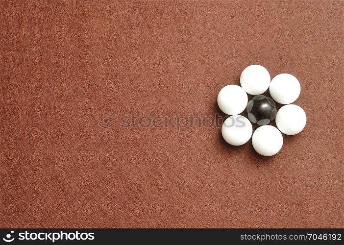 White and black balls packed in the shape of a flower isolated on a brown background