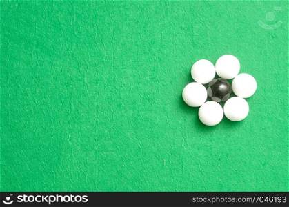 White and black balls packed in the shape of a flower isolated on a green background