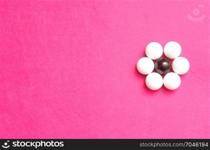White and black balls packed in the shape of a flower isolated on a pink background