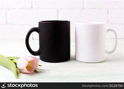 White and black coffee mug mockup with tender pink tulip flower. Empty mug mock up for design promotion. . White and black mug mockup with pink tulip
