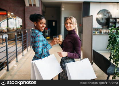 White and black female customers with shopping bags in mall. Shopaholics in clothing store, purchasing, fashion