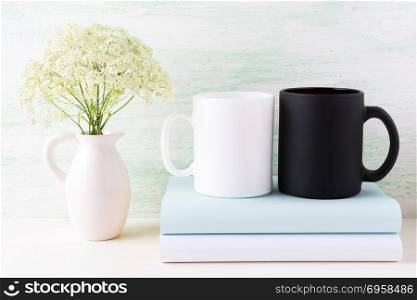 White and black mug mockup with books and white flowers. Empty mug mock up for design promotion. . White and black mug mockup with books and white flowers