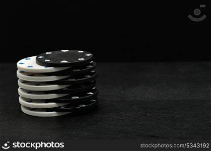 White and black poker chips on a black background