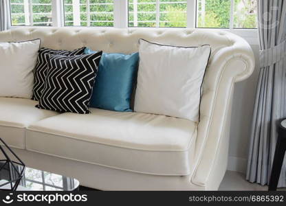 white and blue pillows on a white leather couch in vintage living room