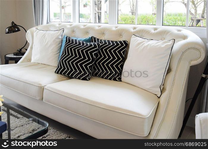 white and blue pillows on a white leather couch in vintage living room