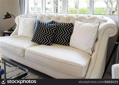 white and blue pillows on a white leather couch in vintage living room