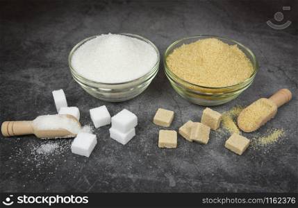 White and brown sugar cubes and heap of sugar on bowl and wooden scoop on table background