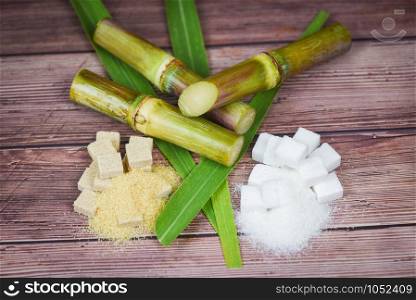 White and brown sugar cubes and sugar cane on wooden table background , top view