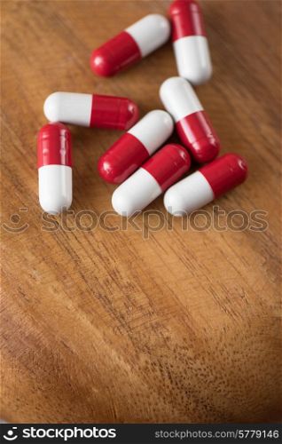 White and red pills on wooden background.. White and red pills