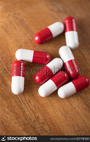 White and red pills on wooden background.. White and red pills