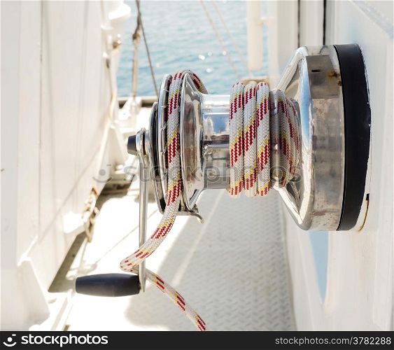 White and red rope on winch with hand crank on a vessel