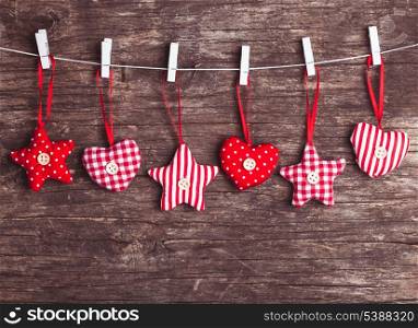White and red sewed christmas decor attached to the rope, over wooden background