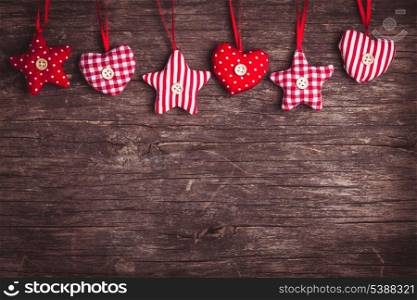 White and red sewed christmas decor attached to the rope, over wooden background