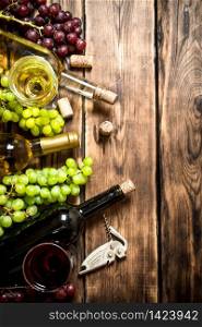 White and red wine with branches of grapes , a corkscrew and corks. On a wooden table.. White and red wine