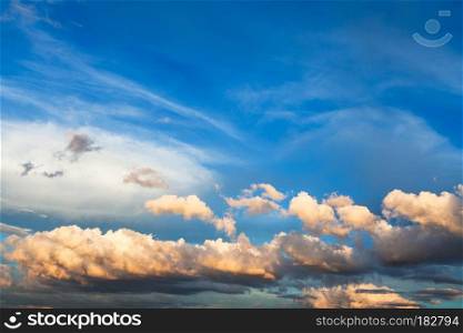 white and yellow cumuli clouds in dark blue sky over Moscow at summer sunset