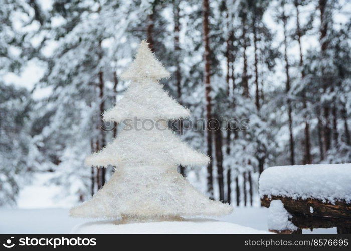 White artificial fir tree stands on wooden branch, covered with snow. Christmas or New Year decor. Season concept. Beautiful winter landscapes. Frosty weather