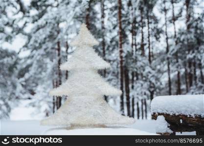 White artificial fir tree stands on wooden branch, covered with snow. Christmas or New Year decor. Season concept. Beautiful winter landscapes. Frosty weather