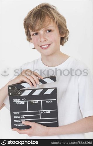 White background studio photograph of young happy boy smiling hand holding a filmmaker&rsquo;s clapperboard