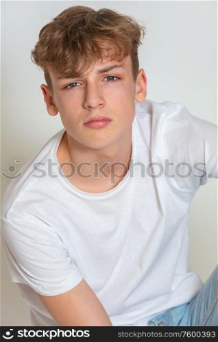 White background studio photograph of young thoughtful moody boy male teen teenager young adult wearing jeans and a white t-shirt