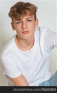 White background studio photograph of young thoughtful moody boy male teen teenager young adult wearing jeans and a white t-shirt