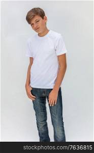 White background studio portrait of a boy teenager teen male child wearing a white t-shirt and blue jeans
