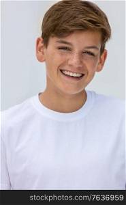 White background studio portrait of a smiling happy boy teenager teen male child with perfect teeth wearing a white t-shirt