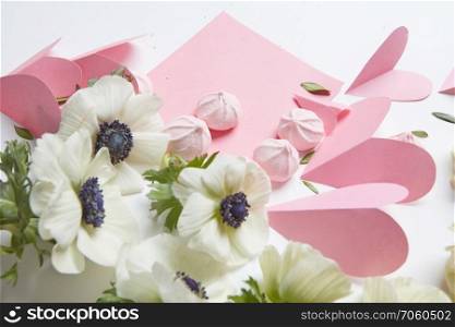 white background with a white flowers and paper hearts with meringue. concept valentine card