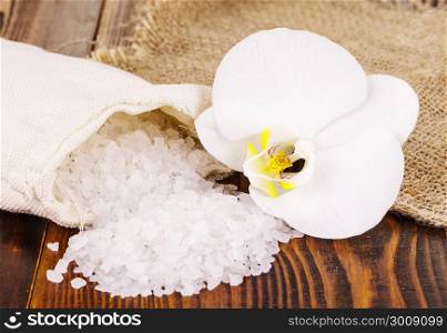 white bath salt and a bag with Orhid on wooden surface