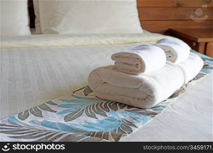 white bath towels rolled and piled on the bed