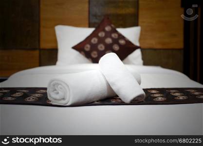 white bath towels rolled and piled on the bed