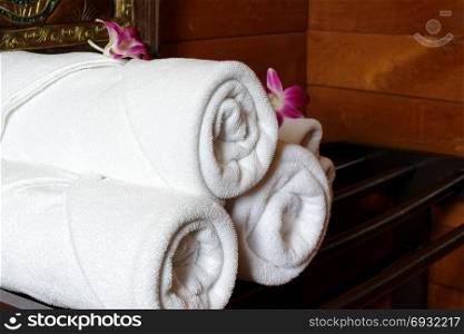 white bath towels rolled and piled on towel rack