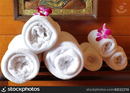 white bath towels rolled and piled on towel rack