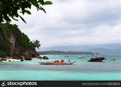 White beachDiniwid beach. Beach in cloudy weather. Boats near the shore.es of Boracay Philippines. Turquoise sea. Green palm trees. BORACAY, PHILIPPINES - Jan 28, 2018: Diniwid beach. Beach in cloudy weather. Boats near the shore.