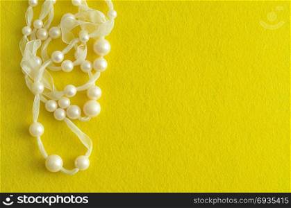 White beads displayed on a white ribbon isolated on a yellow background