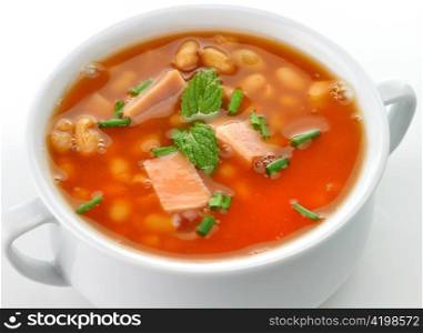white bean soup with ham and tomatoes in a white soup cup